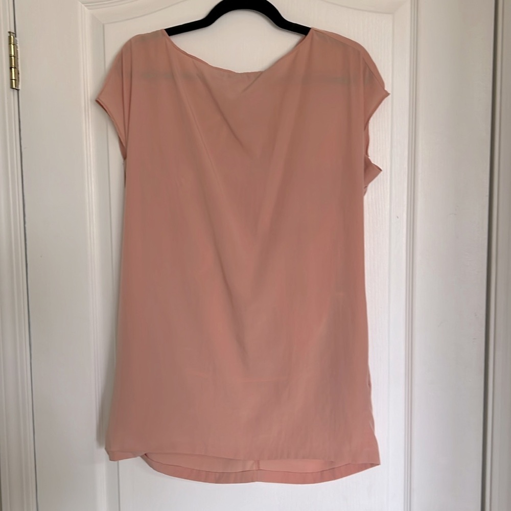 Peach top with pockets and bow detail on back.